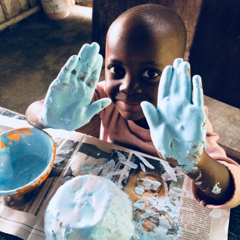 Blandina putting the finishing touches on her paper mache bowl! Couldn't find colored paint so mixed food coloring into white paint!